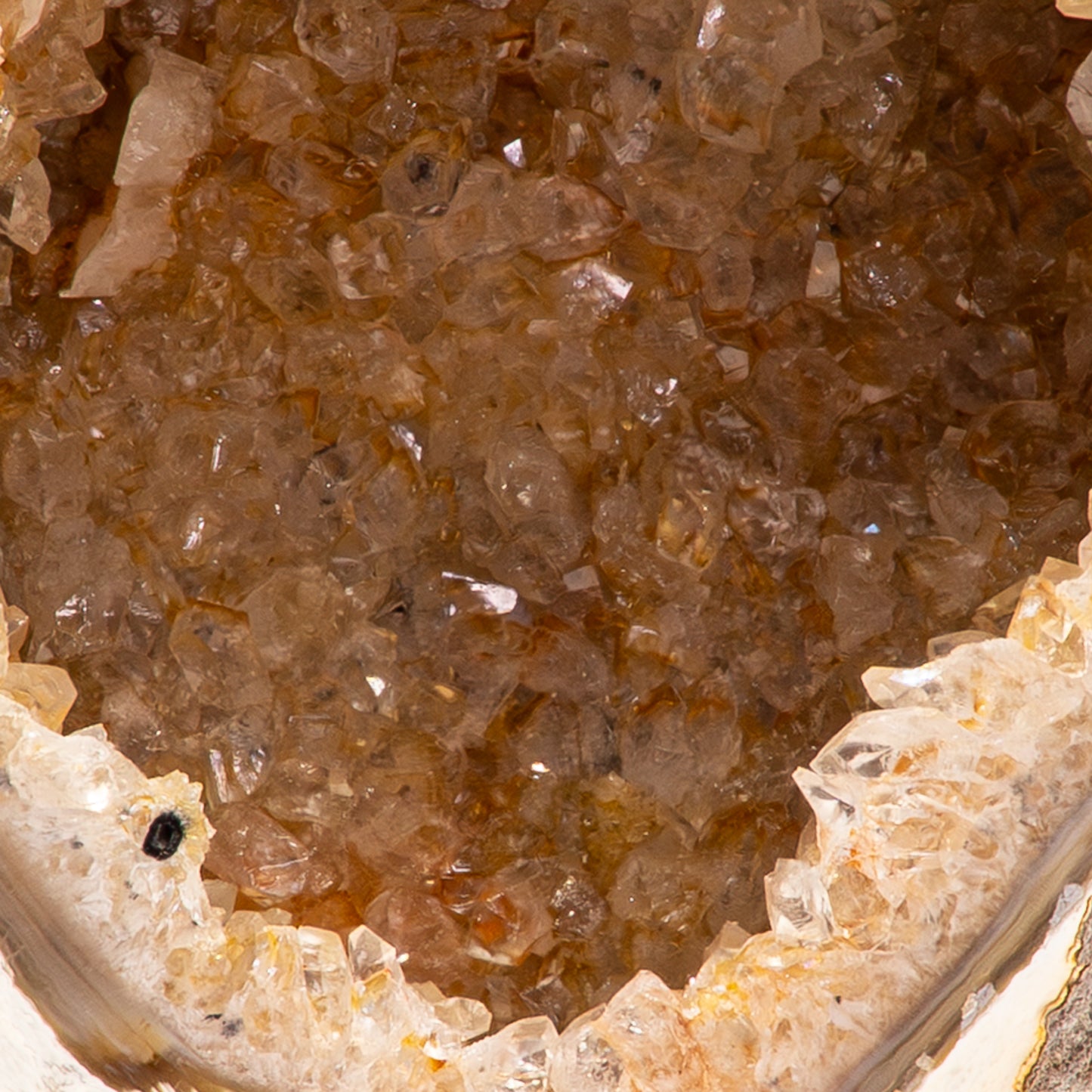 Agaat geode uit Brazilië op zwarte standaard met witte kristallen en een zachte oranje gloed.