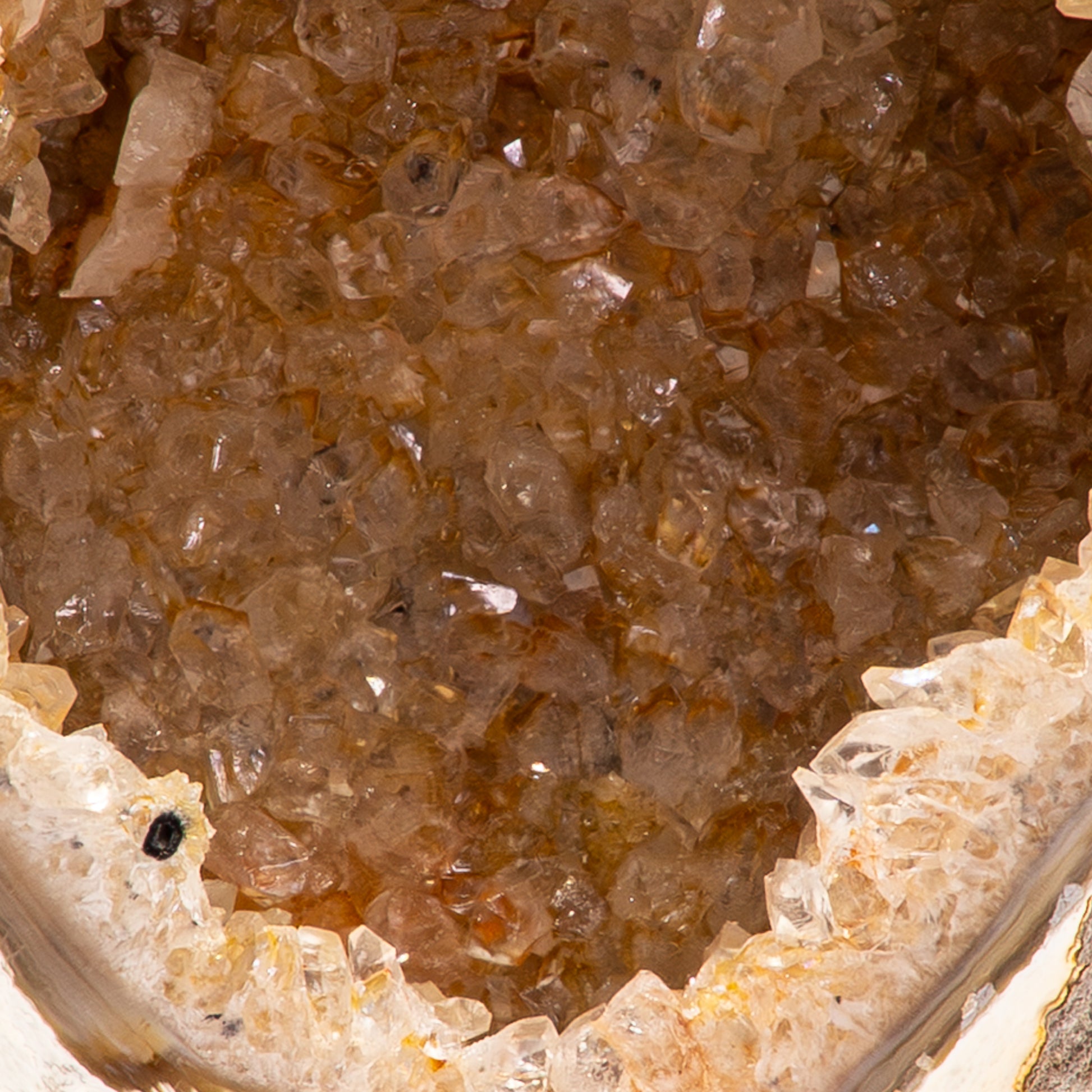 Agaat geode uit Brazilië op zwarte standaard met witte kristallen en een zachte oranje gloed.