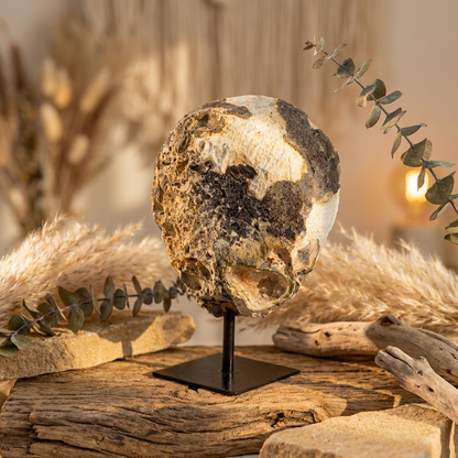 Agaat geode uit Brazilië op zwarte standaard met witte kristallen en een zachte oranje gloed.